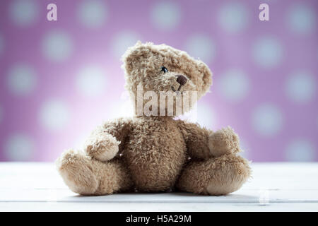 Teddy bear sitting on white wooden desk Stock Photo
