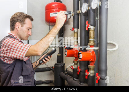 Plumber at  work measures the temperature in a boiler room Stock Photo