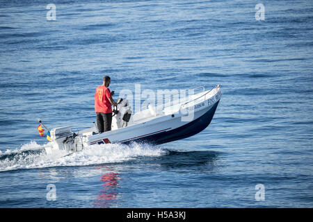 Man looking at mobile phone while at the controls of a speedboat Stock Photo