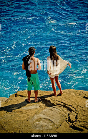 Young couple standing on the edge of a rock by the ocean near Honolulu, Hawaii Stock Photo