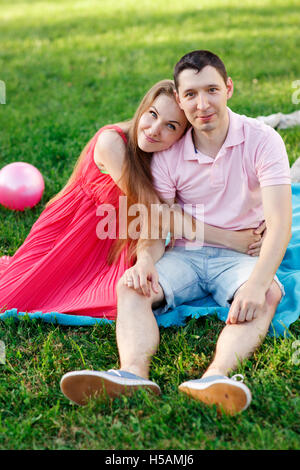 Young girl hugging guy sitting on blue blanket Stock Photo