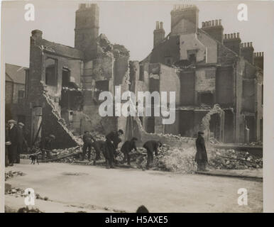 This photograph captures individuals searching through rubble, likely after a disaster or bombing. The scene reflects efforts to locate survivors or valuable items among the debris in the aftermath of destruction. Stock Photo