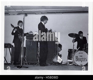 A photograph of Paul McCartney, George Harrison, and Ringo Starr performing at King's Hall, Belfast, in 1964, capturing a moment from The Beatles' iconic tour during the height of their popularity. Stock Photo