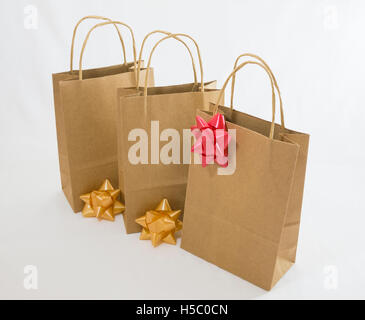 Three paper bag parcels and bows on white background Stock Photo