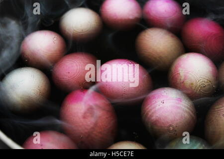 close up portrait of colored eggs boiling in water as steam rises Stock Photo