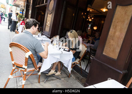 Young woman writing / paying a check in a restaurant in New York City - outdoor sitting area Stock Photo