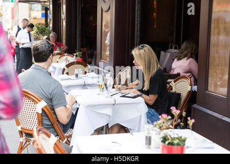 Young woman writing / paying a check in a restaurant in New York City - outdoor sitting area Stock Photo