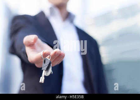 Real estate agent giving keys with buildings background Stock Photo