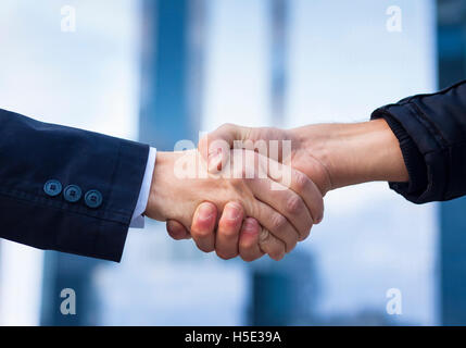 Two businessmen shaking hand with office buildings in background Stock Photo