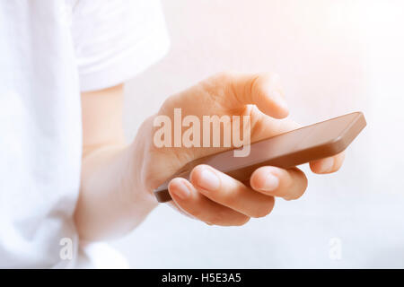 Using smartphone with one hand in bright interior at sunset Stock Photo