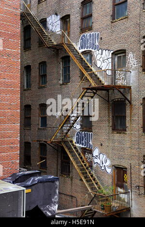 Fire escape and graffiti on the wall of an old apartment building, Chelsea, New York City, NY, USA Stock Photo