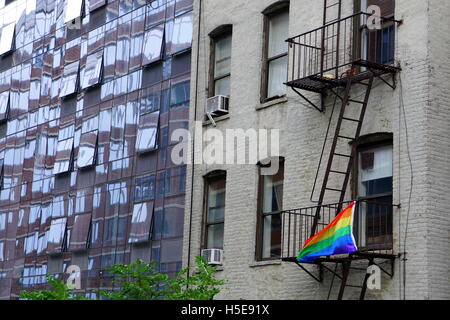 Gay pride flag (rainbow flag) hanging on the fire escape of an old apartment building, Chelsea, New York City, NY, USA Stock Photo