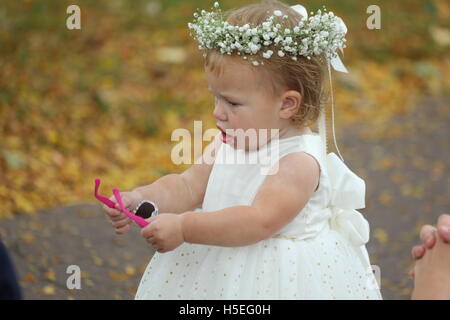 Little girl in white dress is holding sun glasses Stock Photo