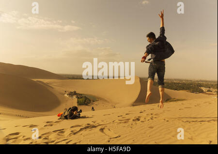 Dunhuang, Dunhuang, China. 25th Sep, 2016. Dunhuang, CHINA-September 25 2016: (EDITORIAL USE ONLY. CHINA OUT) .A tourist poses for a photo at Echoing-Sand Mountain in in Dunhuang, northwest China's Gansu Province, September 25, 2016. Stunning scenery of Echoing-Sand Mountain and Crescent Lake attract lots of tourists from different areas. © SIPA Asia/ZUMA Wire/Alamy Live News Stock Photo