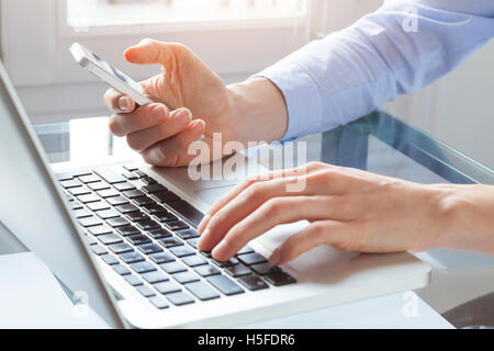 Woman working with smartphone and laptop computer at home Stock Photo