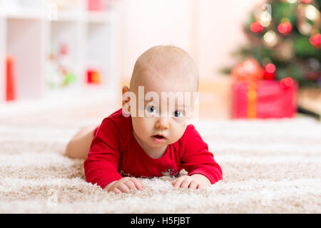 Cute baby boy lying on tummy in front of Christmas tree Stock Photo