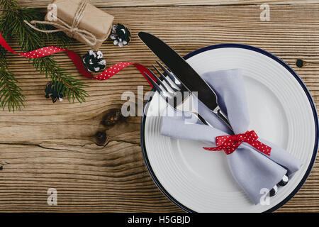 Rustic Christmas place setting,  plate, knife and fork wrapped with napkin on rustic wooden table, top view Stock Photo