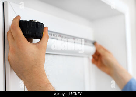 Man installing cassette roller blinds on windows. Stock Photo