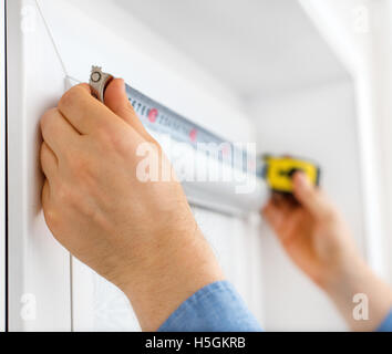 Man installing cassette roller blinds on windows. Stock Photo