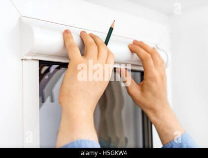 Man installing cassette roller blinds on windows. Stock Photo