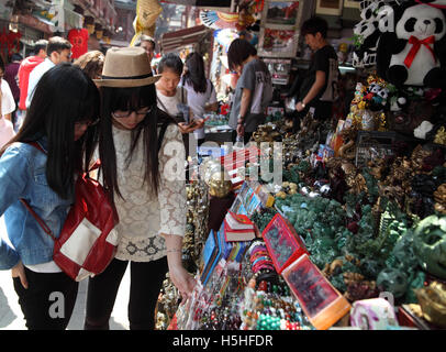 Two young Chinese women look at souvenirs at a stand outside a small shop in the historical Yuyuan Quarter. Shanghai, China. Stock Photo