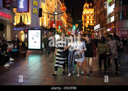 Four young Chinese women and many others roam along the fashionable Nanjing Street in the evening of a holiday weekend.