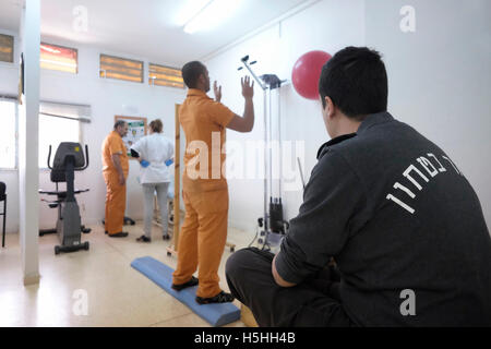 A warder of the Israel Prison Service commonly known in Israel by its acronym Shabas or ISP in English guard as prisoners get physical therapy at the clinic of Eshel prison near the city of Beersheba southern Israel Stock Photo