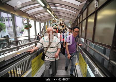 People on an escalator, some stand like this old man, others rush by and take over. Central to Mid-Levels Escalator and Walkway System. Hong Kong. Stock Photo