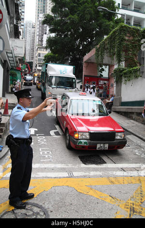 A Chinese policeman directing traffic gesturing cars to stop and wait or go forward Hong Kong, Hong Kong. 06.05.2016 Stock Photo