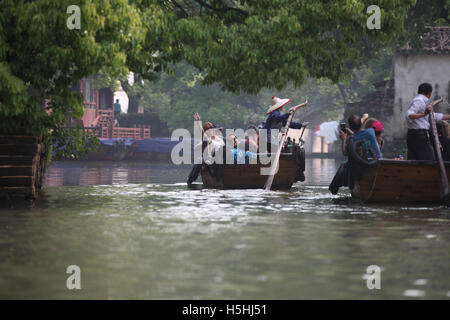 Israeli tourists ride boats in a Tongli canal, an old Chinese town near Suzhou, in one of the boats a woman is rowing, in the other a man. China. Stock Photo