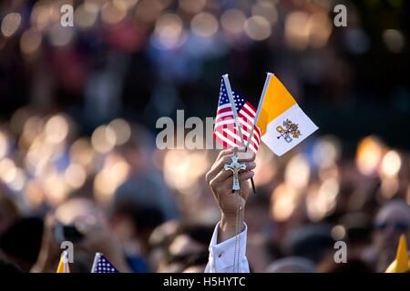 A guest holds up the American flag, the Vatican City flag, and a cross during the State Arrival Ceremony for Roman Catholic Church Pope Francis at the White House South Lawn September 23, 2015 in Washington, DC. Stock Photo