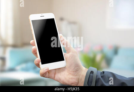 Using white silver smart phone in room. Blank screen of mobile device for mock-up. White background. Room interior in background Stock Photo