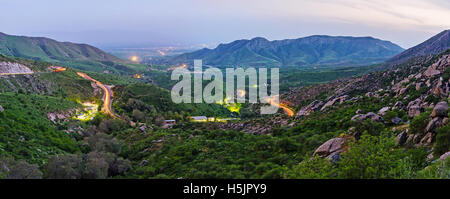 Panorama of the evening Tahtakaracha pass, with the lights on the road and foggy mountains on the background, Uzbekistan. Stock Photo