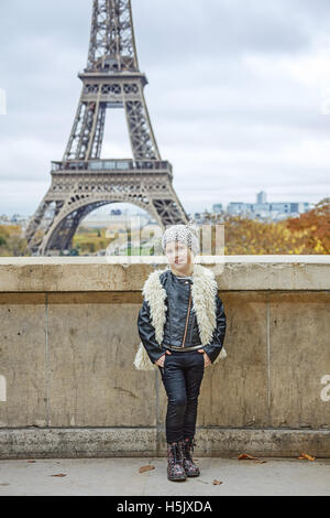 Bold Winter in Paris. Full length portrait of smiling trendy child in the front of Eiffel tower in Paris, France Stock Photo