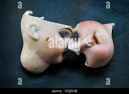 Broken vintage doll face parts on grunge background Stock Photo