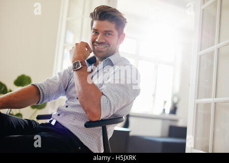 Portrait of handsome young man sitting at home and smiling. Caucasian man looking happy. Stock Photo