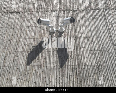 Two security cameras on grey concrete building wall Stock Photo