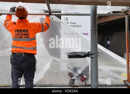 Scaffolding with sheeting is erected outside Lunar House in Croydon, south London, to offer privacy to migrants being taken off coaches as more migrants are due to arrive from the 'Jungle' camp in Calais. Stock Photo