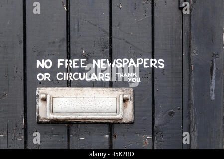 Hand painted sign reading No Free Newspapers or Circulars Thank You, next to letterbox on a black door. Stock Photo