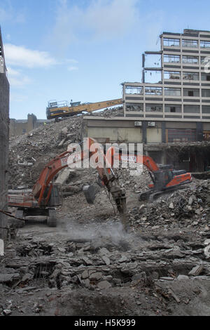 Heavy plant machinery wrecking and breaking up buildings on an inner city demolition site that looks like a war zone. Stock Photo