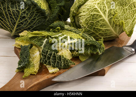 organic savoy cabbage is cut on a wooden board in small strips and prepared for cooking Stock Photo