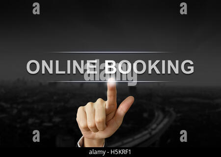 business hand clicking online booking button on black blurred background Stock Photo
