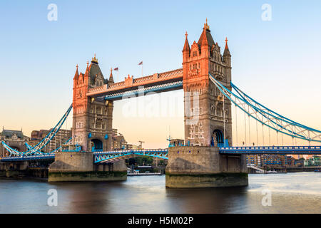 Tower Bridge in London at sunset, casting a orange light on part of the bridge Stock Photo