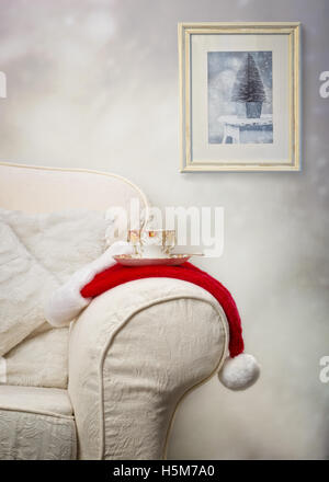 Cup of tea on santa hat with Christmas picture hanging in the background Stock Photo