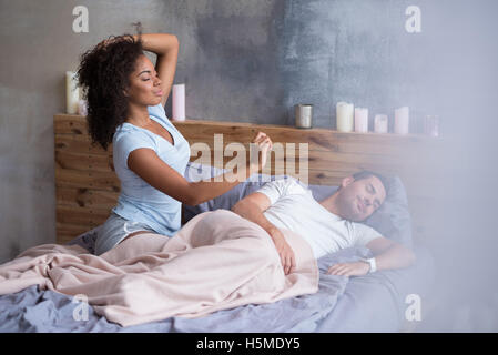 Sleepy girl waking up while her husband is sleeping Stock Photo