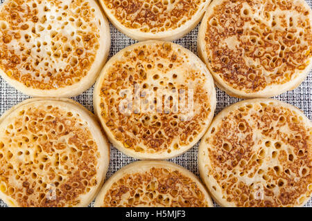 Close up of fresh golden crumpets on a black and white woven table mat