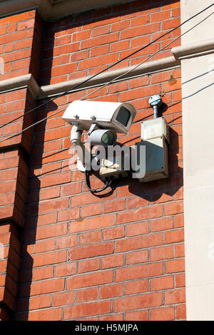 A surveillance CCTV camera attached to the side of a building Stock Photo