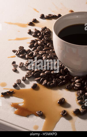 Coffee beans, white coffee cup with spilled coffee Stock Photo