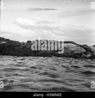 A photograph capturing the view of a rocky ledge at Sherman's Point in Camden, Maine, overlooking the scenic Camden Harbor, known for its natural beauty and coastal landscape. Stock Photo
