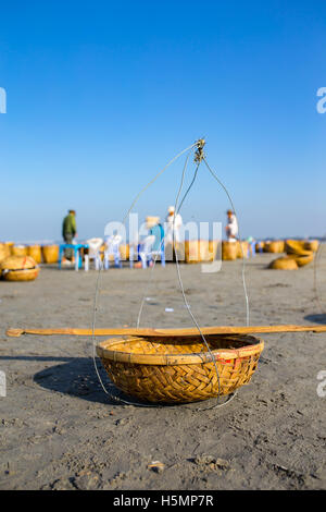 Fishing basket with two woman, wearing conical hat in background under blue sky at Long Hai beach, Ba Ria, Vung Tau, VietNam Stock Photo